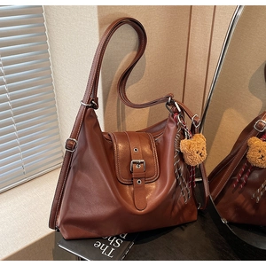 Details der braunen Vintage-Leder-Einkaufstasche mit Zierschnalle und Plüschbär-Anhänger