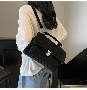 Detail of black frosted suede messenger bag with silver metal lock and top handle
