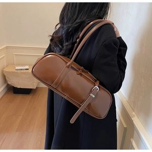 Close-up of gloss brown underarm bag with thin shoulder straps and silver buckles