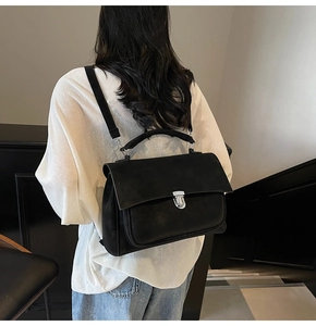 Detailed back view of a black matte textured backpack with a large flap and silver metal lock