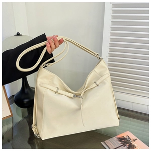 Close-up of cream leather tote bag featuring silver metal rings and fine texture