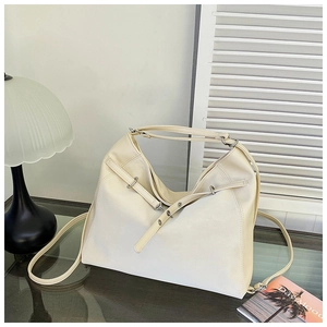 Detail of cream white leather tote bag featuring decorative straps and silver metal buckles