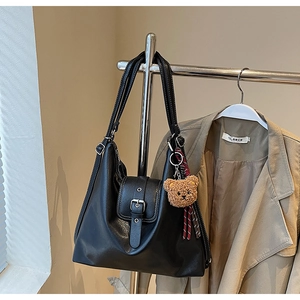 Detail einer großen schwarzen Kunstleder-Tote Bag mit Schnalle und Bären-Anhänger