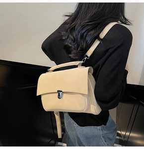 Detailed view of beige faux leather handbag featuring silver buckle and adjustable strap
