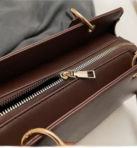Makroaufnahme von glattem Goldreißverschluss und Hardware an brauner Kunstledertasche