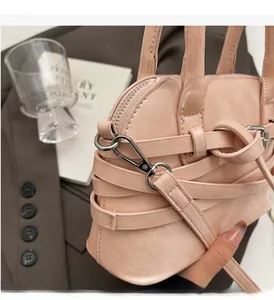Close-up of pink shell handbag with decorative straps and glossy silver hardware on a blazer