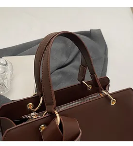 Detail einer braunen matten Ledertasche mit goldenen Ringen und stabilen Doppelgriffen