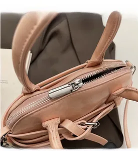 Detailed macro view of the silver metal zipper and smooth stitching on the pink shell bag