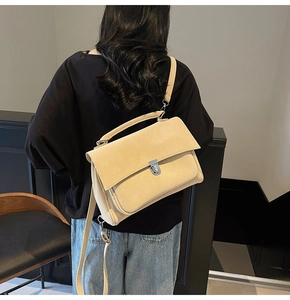 Detail of minimalist cream-colored matte satchel featuring a silver buckle and top handle