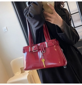 Close-up of deep red patent leather bag with belt buckle and gold key pendant