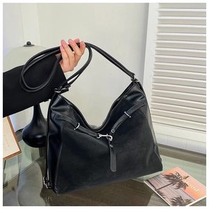 Detailed view of large black leather hobo bag with buckled strap and lychee grain texture