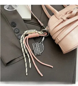 Detail of pink woven bag charm with metal abacus and tennis racket on a stylish handbag