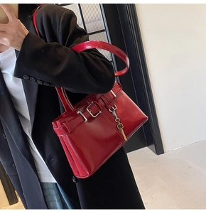 Close-up of red patent leather handbag with silver buckles and a gold key charm