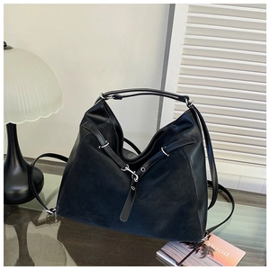Close-up of black leather bag with silver metal buckles and textured stitching detail