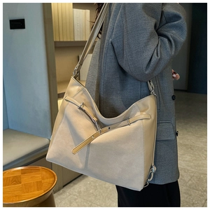 Detail of a large beige leather shoulder bag with silver buckles for daily commute