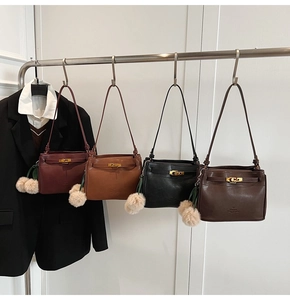 Detail view of four vintage underarm bags with gold turn-locks and fluffy charms on hooks