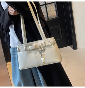 Chic cream leather motorcycle bag styled as a shoulder bag with a silver key charm