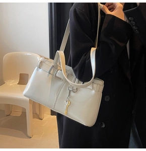 Model wearing a retro cream white faux leather underarm bag with unique key pendant