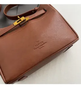 Close-up of brown leather bag featuring golden metal turn-lock and fine grain texture