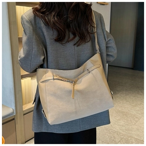 Detailed back view of a large beige tote bag featuring mixed leather and decorative buckles
