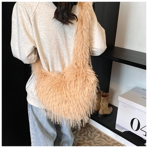 Detail of plush apricot faux fur hobo bag worn by model in a cozy winter setting