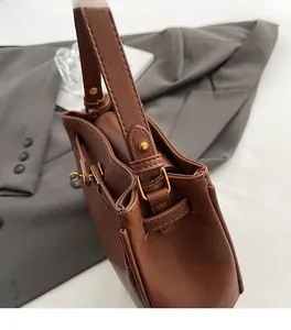 Close-up of premium dark brown leather texture and golden metal buckle on a retro handbag