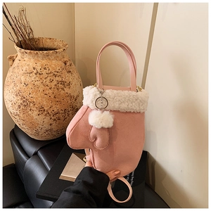 Detailansicht der rosa handtasche in fäustling-form mit weißem kunstpelz und plüschbommel