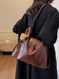 Braune Leder-Einkaufstasche mit Teddybär-Anhänger als Schultertasche am Modell