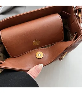 Detail of reddish brown leather handbag featuring magnetic closure and striped lining