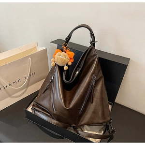 Detail of vintage brown leather tote bag in gift box with orange monster keychain