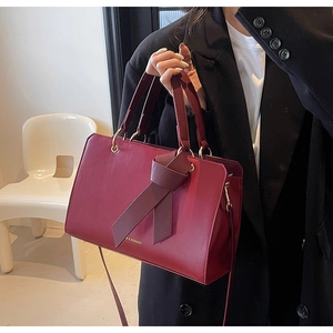 Details der burgunderroten PU-Ledertasche mit eleganter Schleife und goldener Hardware