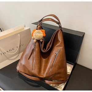 Detail view of brown faux leather hobo bag in gift box with cute orange plush charm