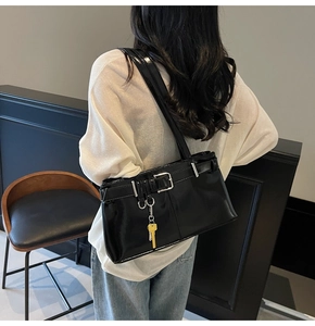 Macro detail of black glossy patent leather shoulder bag with a yellow key charm
