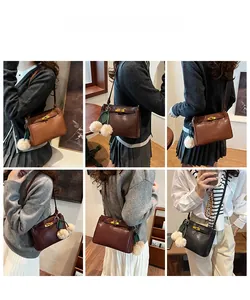 Close-up of vintage matte leather shoulder bags featuring plush ball charms and metal clasps