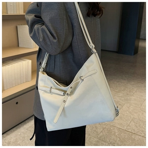 Detail of white PU leather tote bag with unique asymmetric design and metal buckle straps