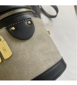 Close-up of black leather and beige canvas bucket bag with gold hardware detail