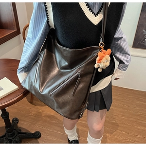 Close-up of vintage dark brown faux leather tote with silver zippers and a plush charm