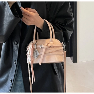 Detail of light pink shell bag with tennis racket charm and woven leather trim