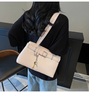Detail of light pink leather shoulder bag with silver buckles and keychain accessory