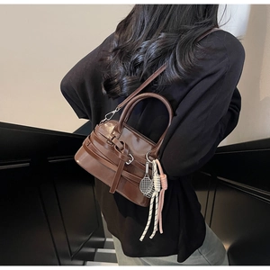 Detail showing the dark brown glossy leather texture and stylish tennis racket pendant