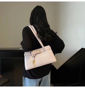 Detail of pink patent leather shoulder bag with belt buckle and metallic key charm