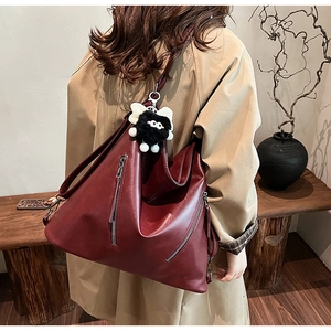 Detailed back view of vintage burgundy leather shoulder bag with plush monster charm