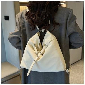 Detail of cream leather backpack on grey blazer showing texture and silver buckles