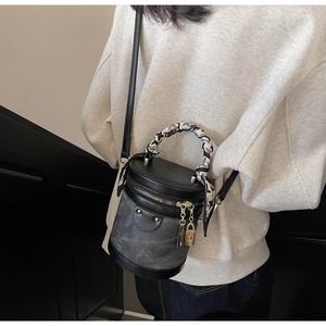 Detail of contrast bucket bag with silk scarf handle and metallic rivet accents