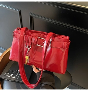 Detail of red patent leather motorcycle bag with belt buckle and metallic key pendant