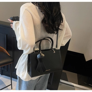 Detailansicht der schwarzen Lederhandtasche mit goldenen Beschlägen und Schultergurt
