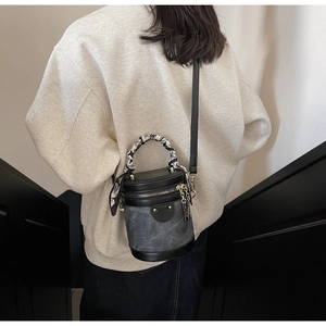 Detail of vintage bucket bag with silk scarf on handle and retro rivets