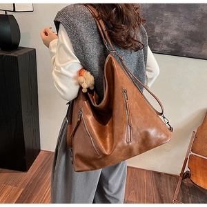 Detail showing vintage brown leather bag with multi-zipper pockets and bear charm