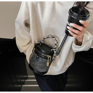 Detail of contrast bucket bag with silk scarf handle and golden hardware accents
