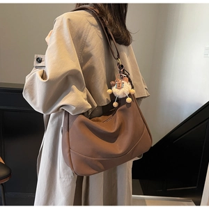 Detail of dark brown hobo bag with soft matte texture and plush lion charm decoration